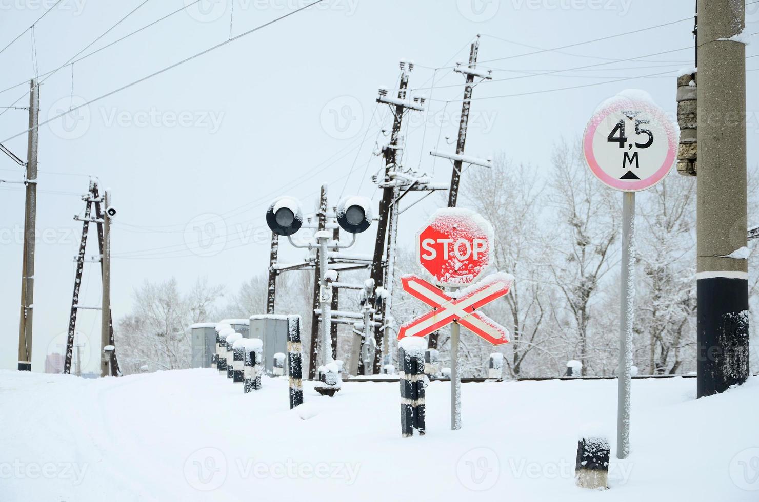 Pause. rotes verkehrsschild befindet sich auf der autobahn, die in der wintersaison die bahnlinie überquert foto