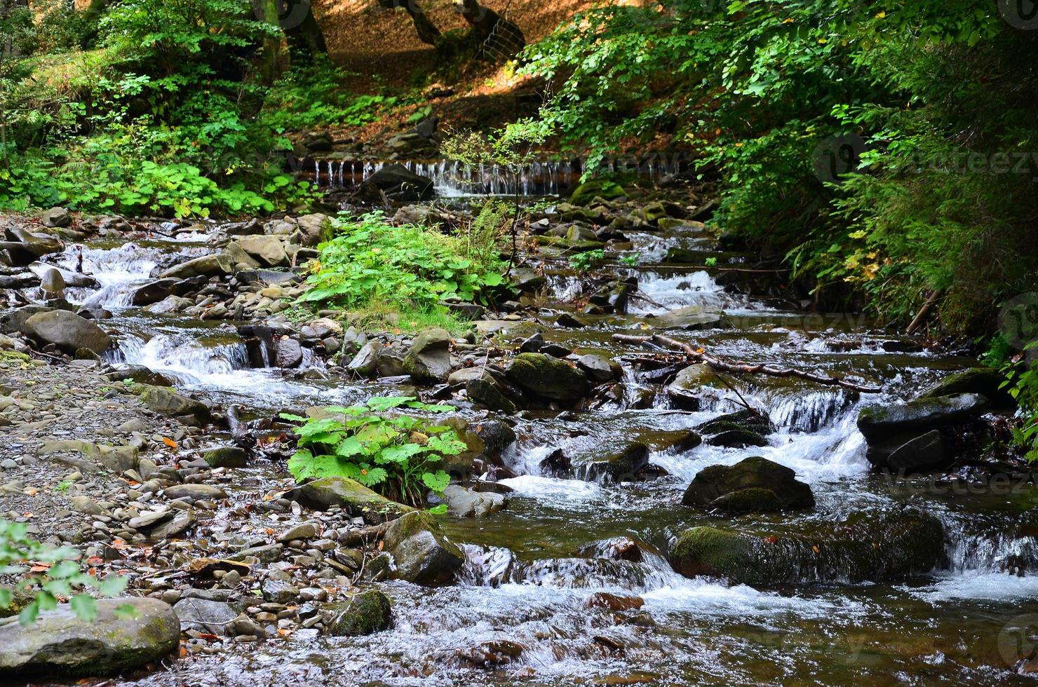 Nahaufnahme eines kleinen wilden Wasserfalls in Form von kurzen Wasserströmen zwischen Bergsteinen foto