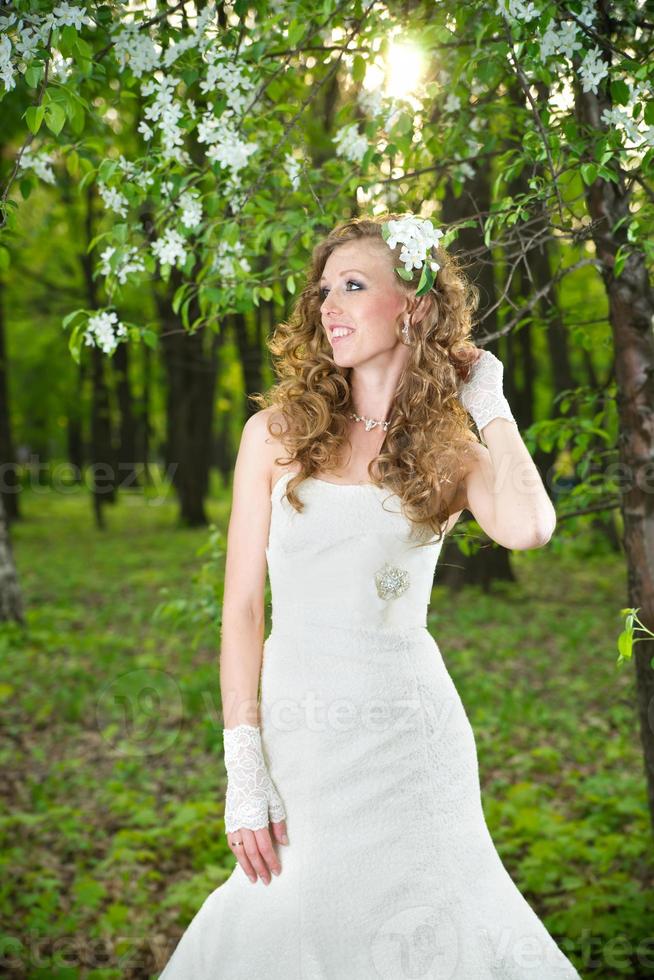 schöne Braut im weißen Kleid auf blühenden Gärten foto
