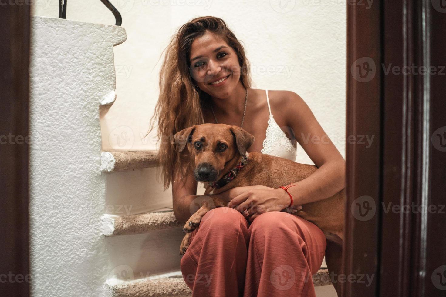 Porträt einer schönen Latina-Frau, die ihren Hund umarmt und beide in die Kamera schaut. foto