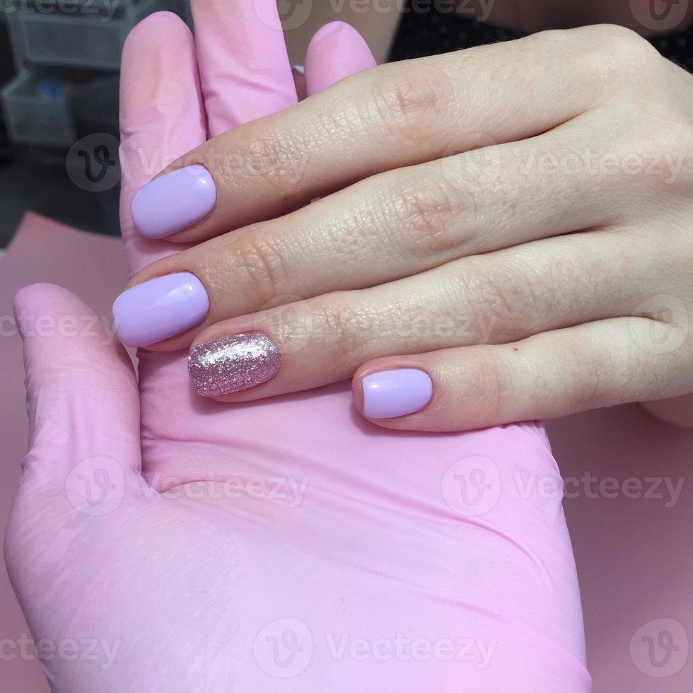 maniküre in verschiedenen farben auf den nägeln. weibliche maniküre auf der hand auf rosa hintergrund foto