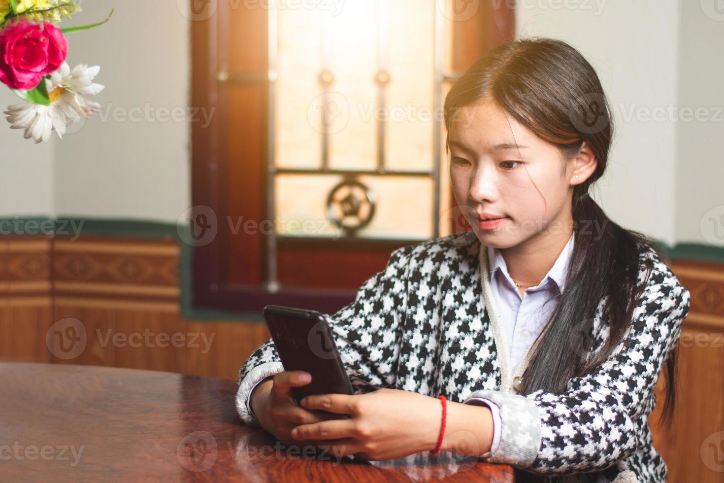 eine junge studentin online chattet mit ihrer freundin auf handy, social media und chat-verbindungskonzept, sonnenlicht durch die fenster kopiert platz für individuellen text foto