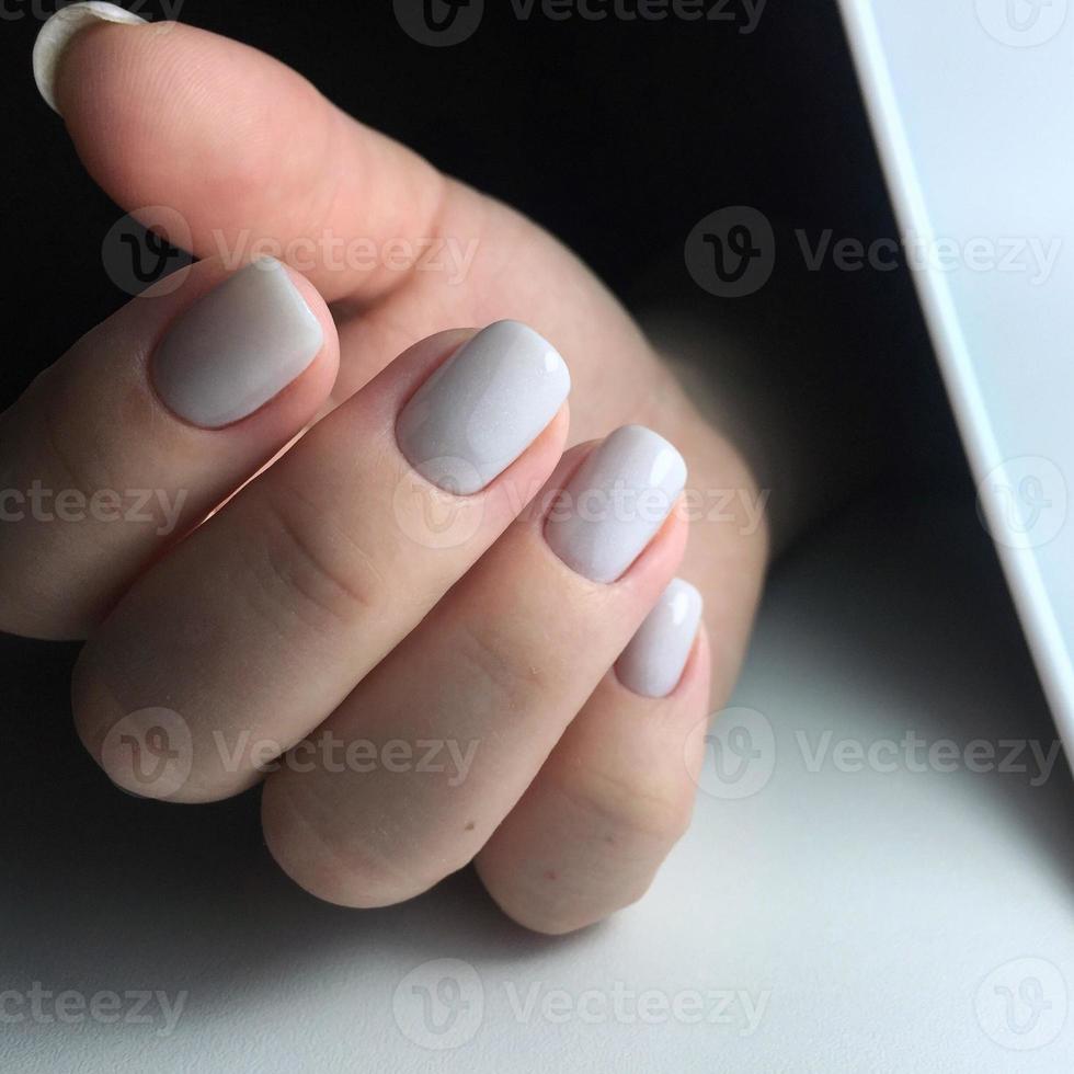 Frauenhände mit weißen Nägeln auf dunklem Hintergrund foto