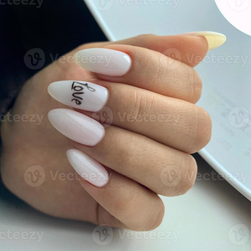weibliche maniküre auf nägeln mit der aufschrift liebe auf dem nagel foto
