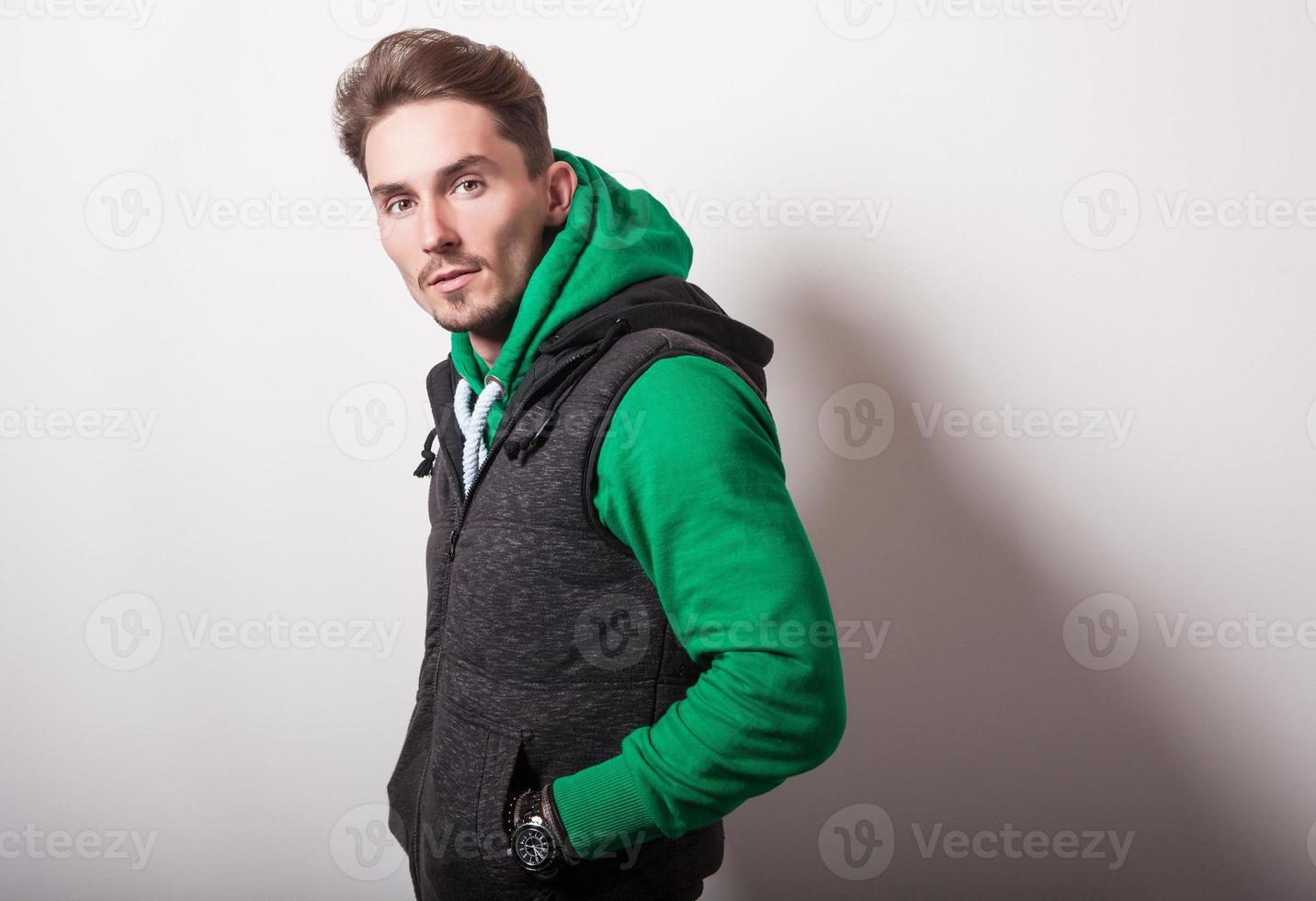 attraktiver junger Mann in grauer Weste & grünem Pullover. foto