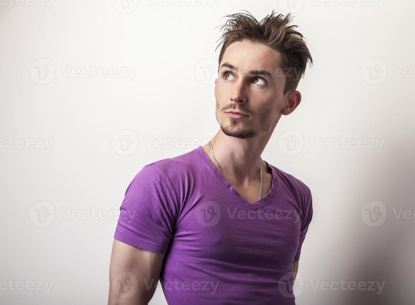 junger hübscher Mann im violetten T-Shirt. foto