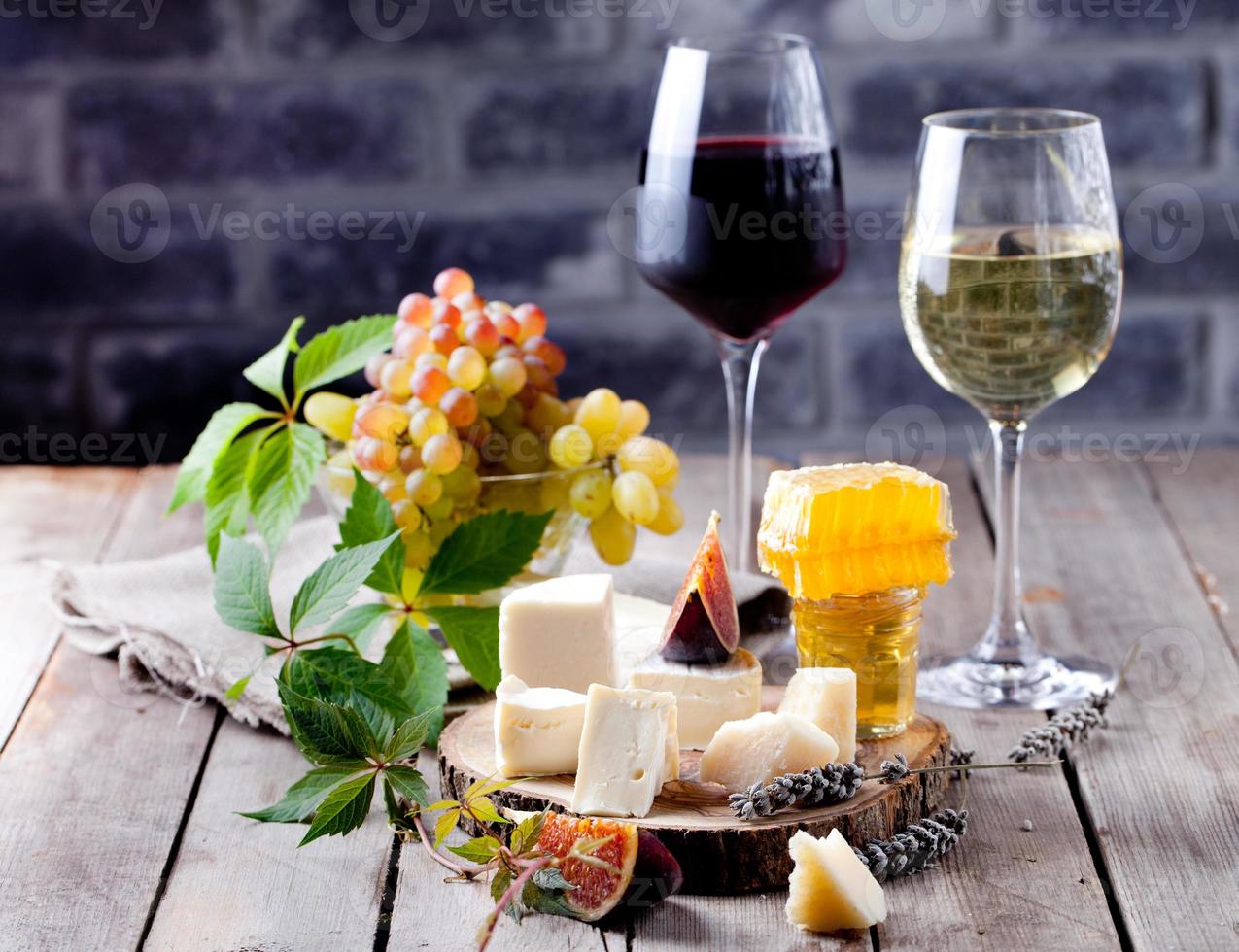Käseteller mit Honig, Traube, Wein in Gläsern foto