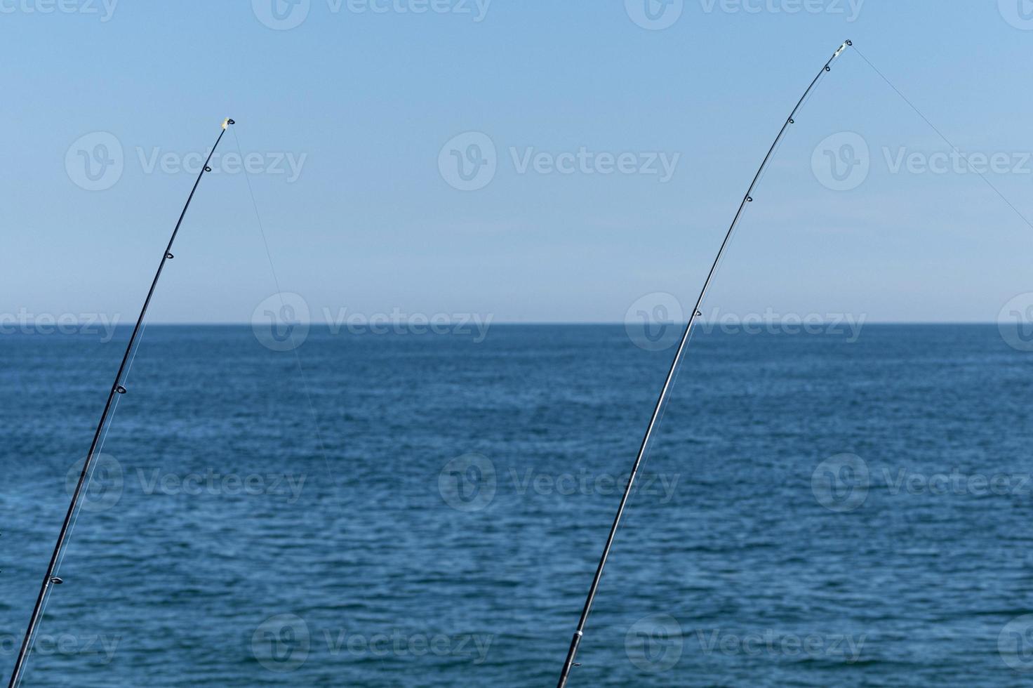 zwei Angelruten vor blauem Ozean- oder Meereshintergrund, Kopierraum. Warten auf den größten Fang. meditativer Entspannungssport. foto