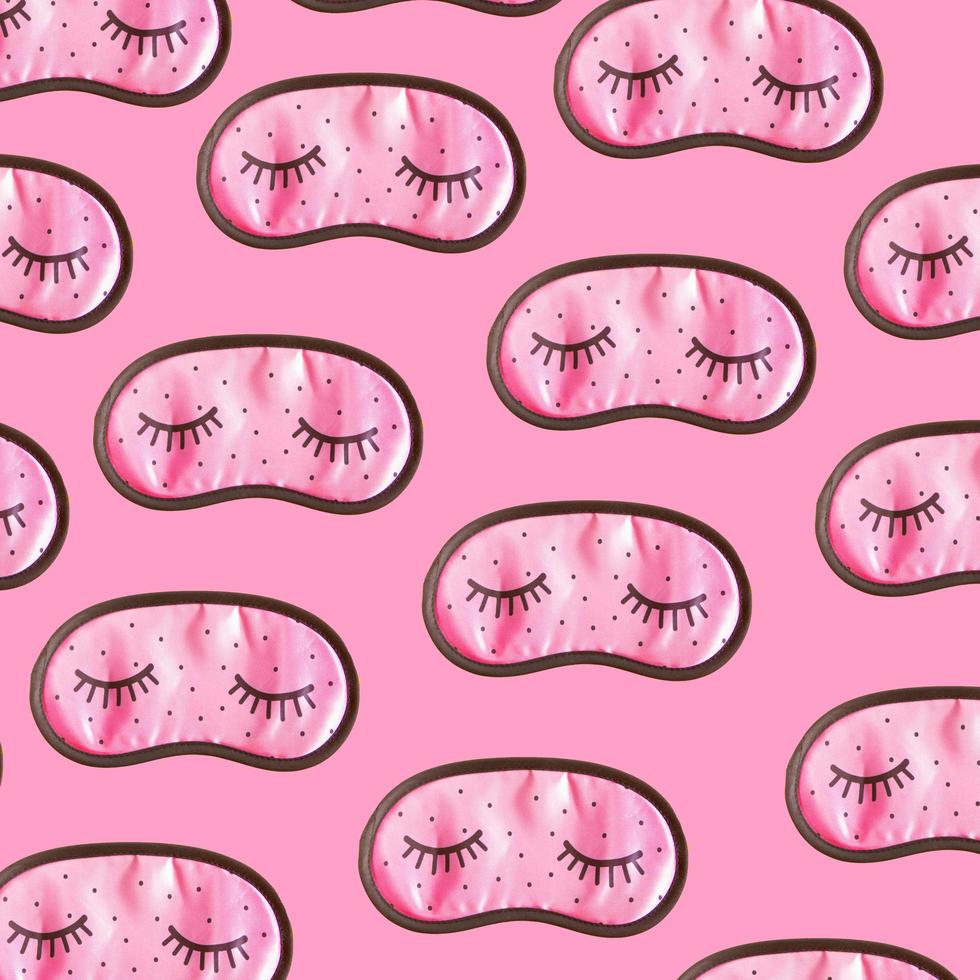 rosafarbenes Schlafmaskenzubehör für Mädchen und junge Frauen mit geschlossenen Augen auf rosafarbenem Hintergrundmuster. Ansicht von oben, flach liegend. konzept des augenschutzes für gute träume und schlaf. foto