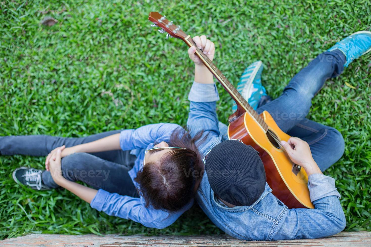 hipster-mann, der gitarre für seine freundin im freien gegen die mauer spielt und zusammen genießt. foto