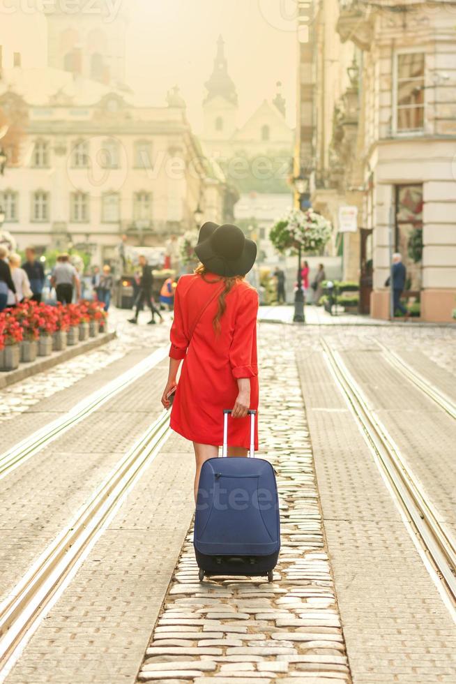 schönes junges Mädchen, das mit blauem Koffer geht. foto