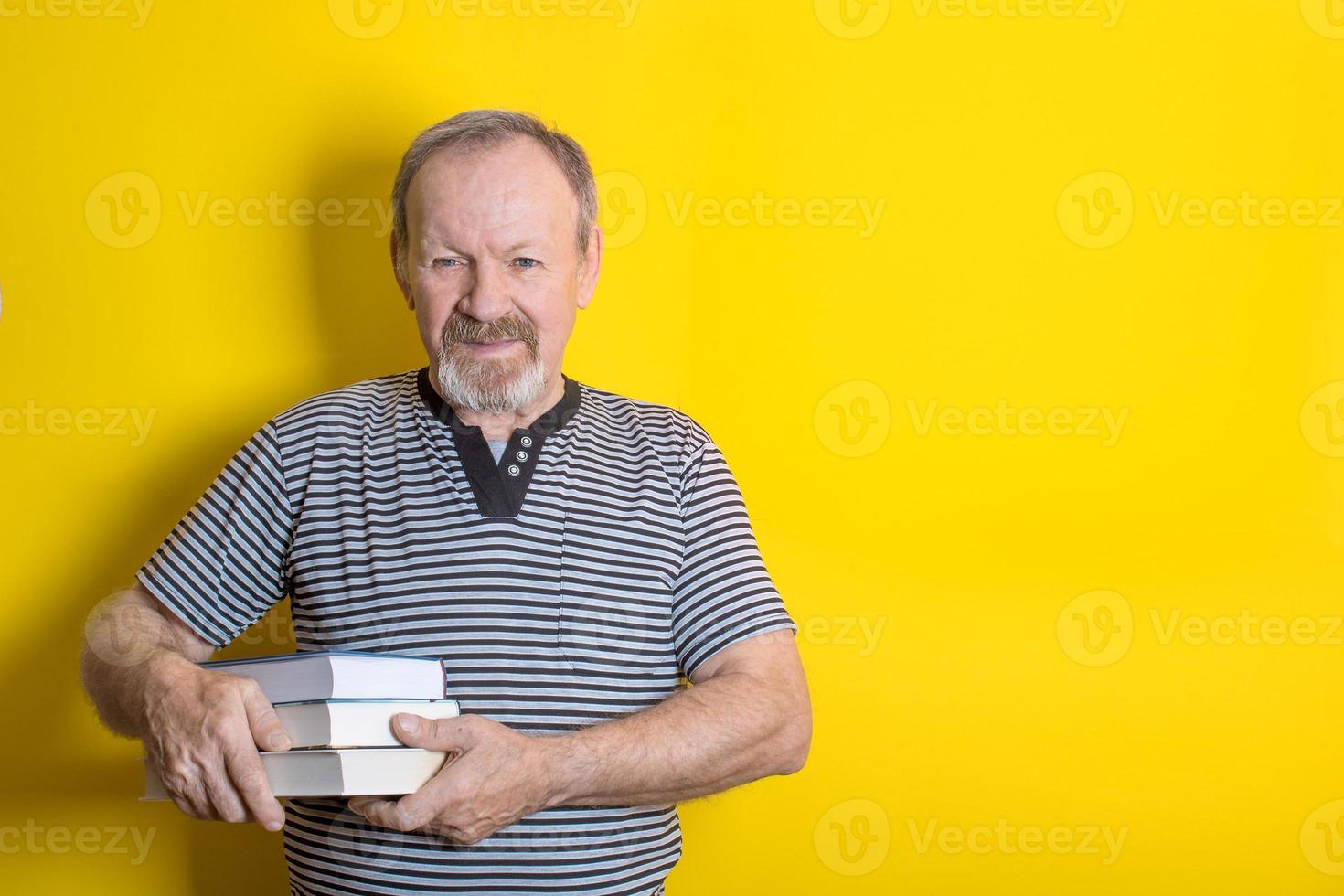 süße ältere männer, die einen stapel bücher auf gelbem hintergrund halten. Platz kopieren foto