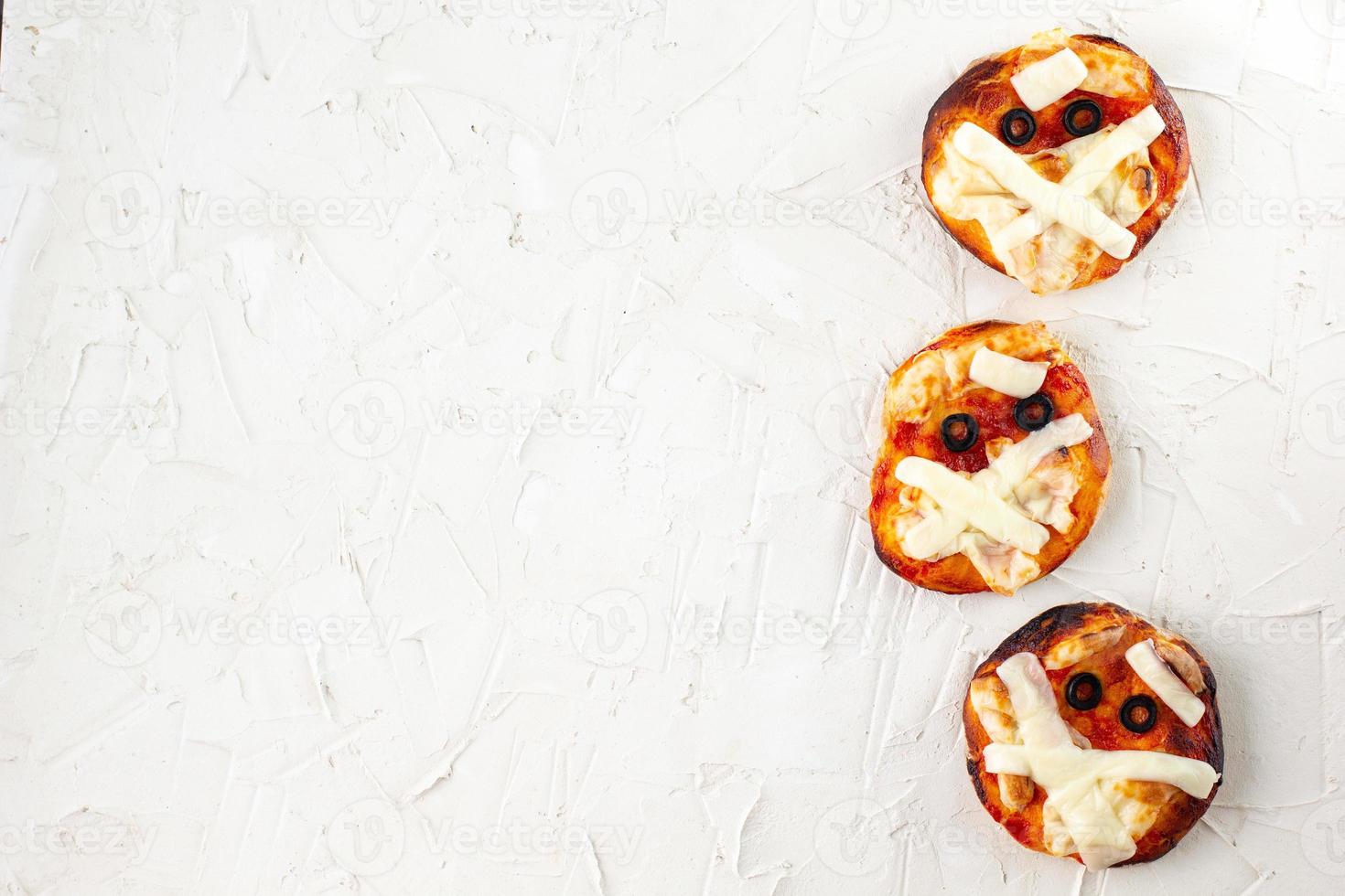 Minipizza als Mama für Kinder mit Käse, Oliven und Ketchup. lustiges verrücktes Halloween-Essen für Kinder foto