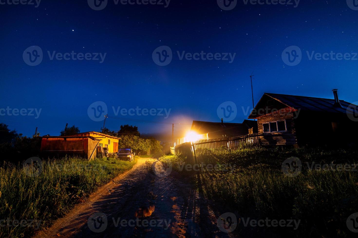 Sternenhimmel über Dorfhaus im Sommer. Holzhaus mit einer Glühbirne über dem Eingang. Russland. foto