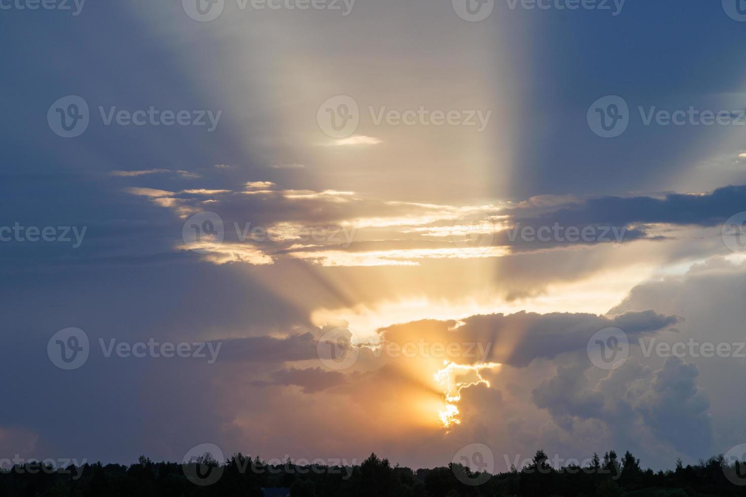 bewölkter sonnenunterganghimmel mit gelben sonnenstrahlen mit horizont foto