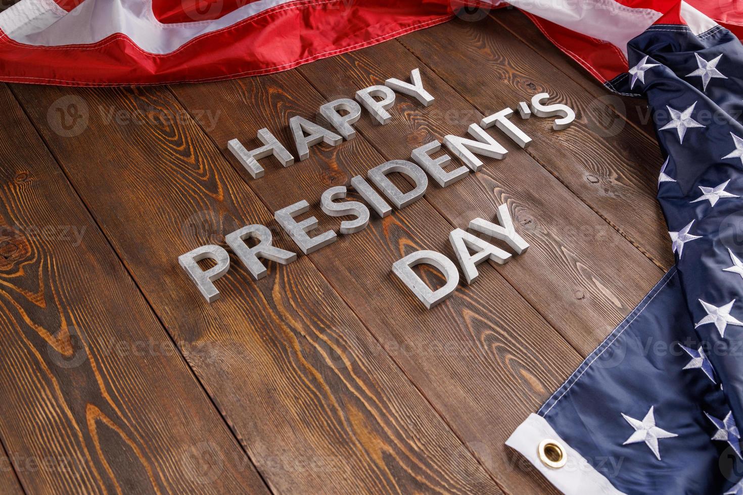 Worte Happy Presidents Day mit echten Buchstaben auf Holzbrett in der Nähe der US-Flagge gelegt foto