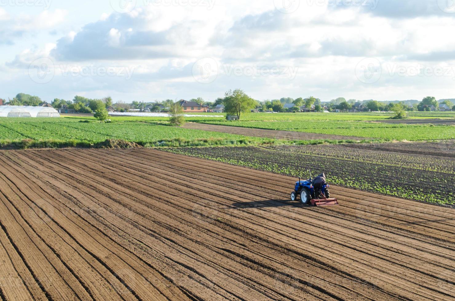 Ein Traktor fährt auf einem Feld. Lockerung der Oberfläche, Kultivierung des Landes für die weitere Bepflanzung. Landwirt auf einem Traktor mit Fräsmaschine lockert, mahlt und mischt Erde. Landwirtschaft und Ackerbau. foto