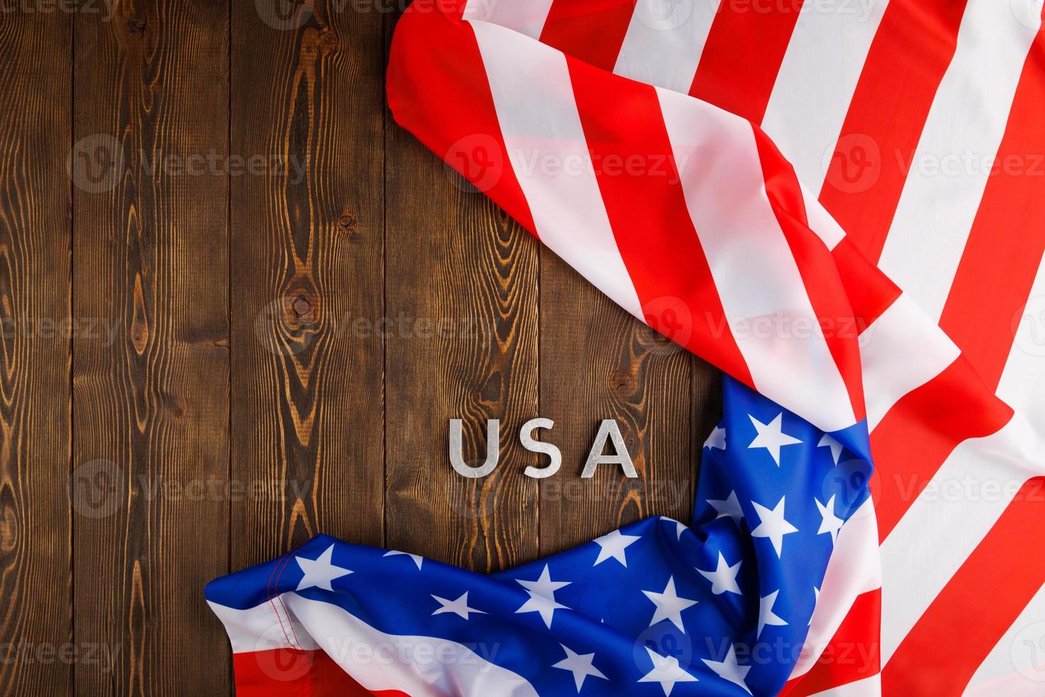 das wort usa mit silbernen metallbuchstaben auf holzbrettoberfläche unter zerknitterter flagge der vereinigten staaten von amerika gelegt foto