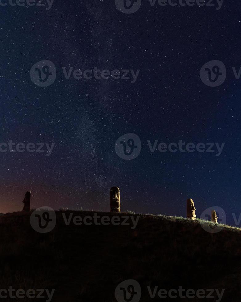 Vier steinerne Köpfe auf einem Hügel in der Nacht foto