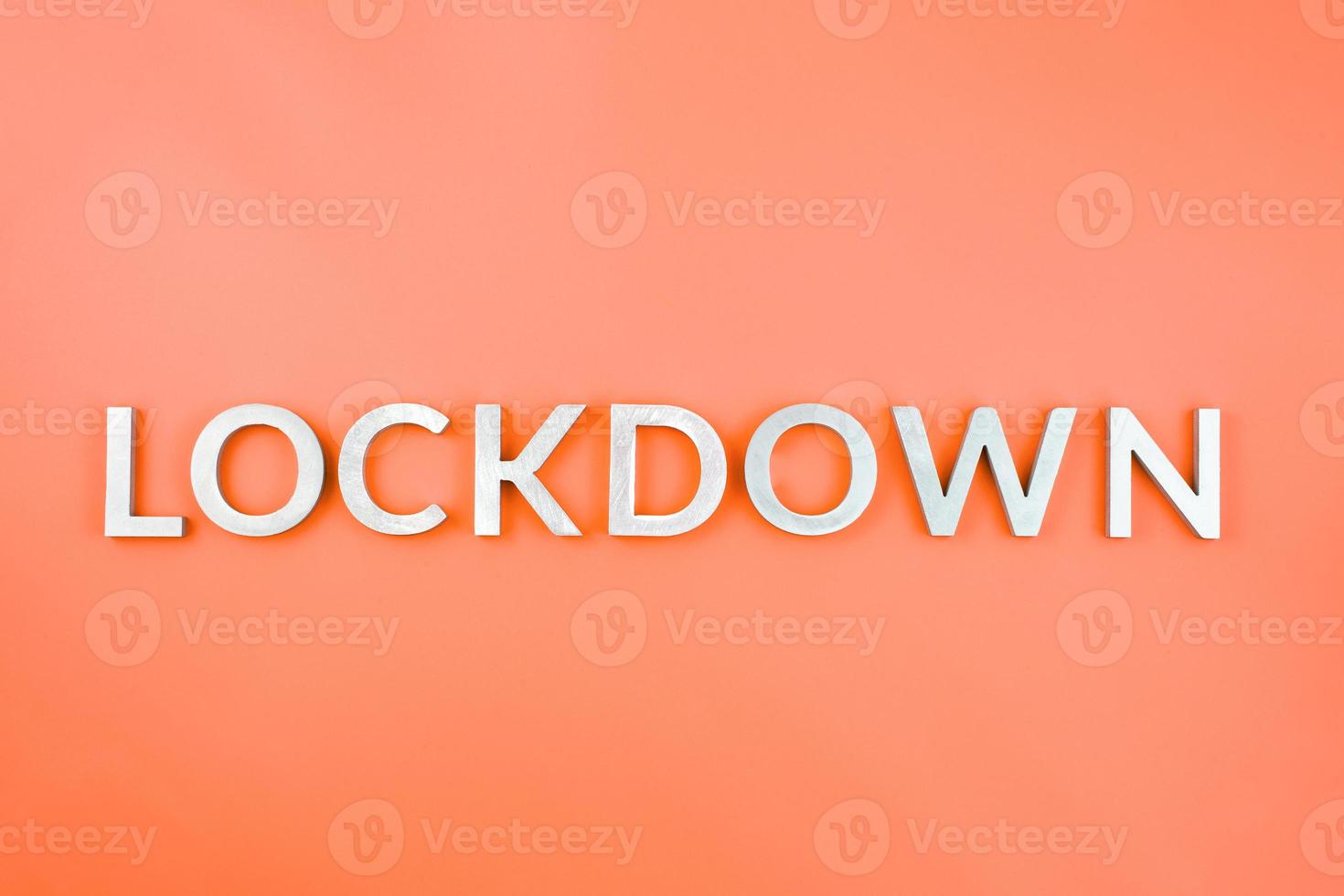 das wort lockdown mit gebürsteten aluminiummetallbuchstaben auf üppigem lava-orangefarbenem hintergrund foto