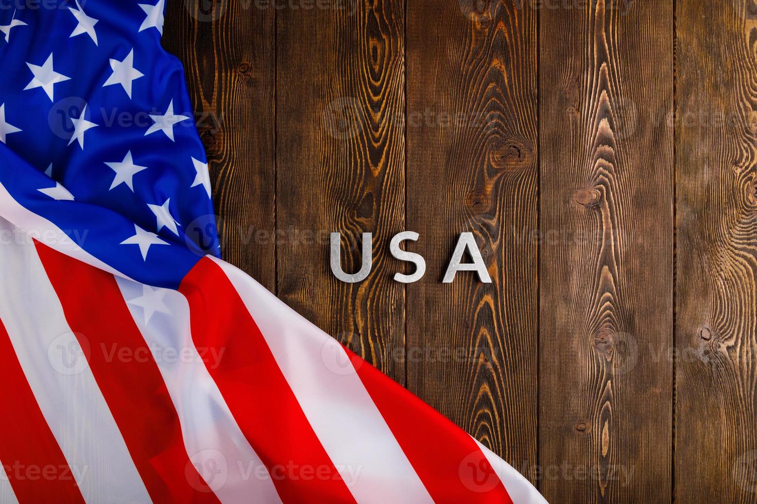 das wort usa mit silbernen metallbuchstaben auf holzbrettoberfläche mit zerknitterter flagge der vereinigten staaten von amerika gelegt foto
