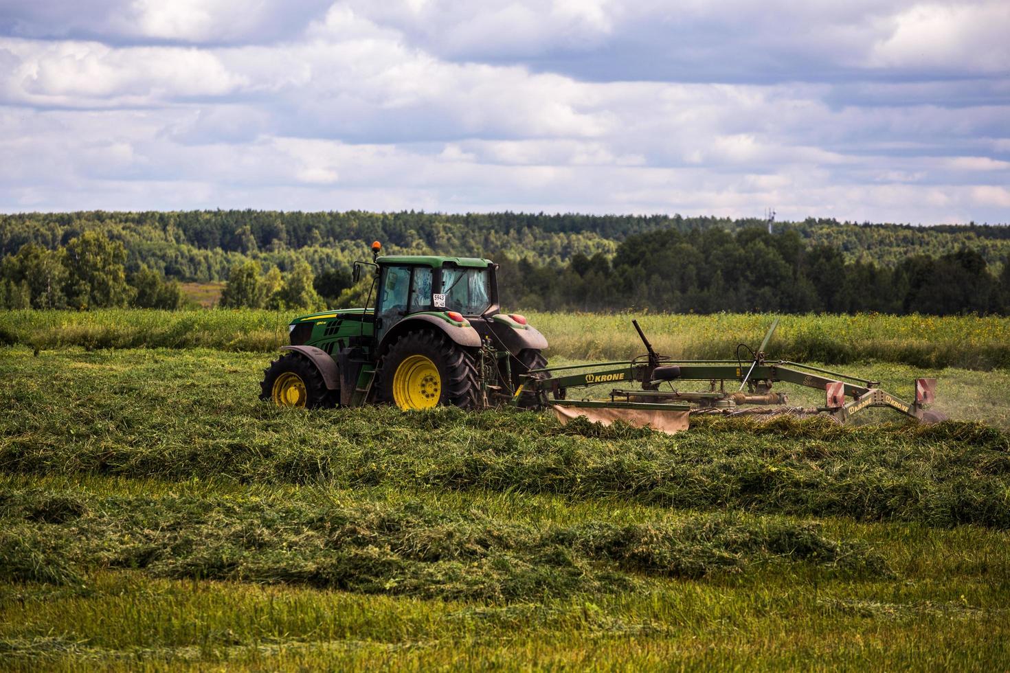 tula, russland 30. juli 2019 grüner heuernter traktor auf sommerfeld vor sturm - teleaufnahme mit selektivem fokus foto