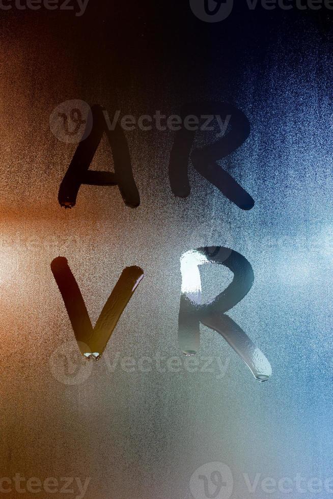 Abkürzungen ar - fugmented reality - und vr - virtual reality - geschrieben mit dem Finger auf nassem Glas mit verschwommenem Hintergrund foto