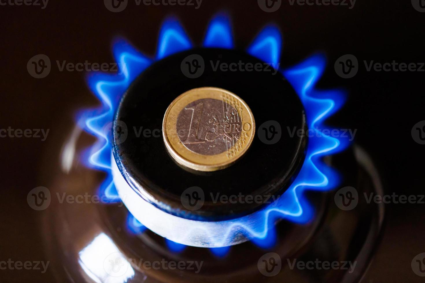 Gasherdbrenner mit einer aufgelegten Ein-Euro-Münze, die Erdgas mit blauer Flamme verbrennt foto