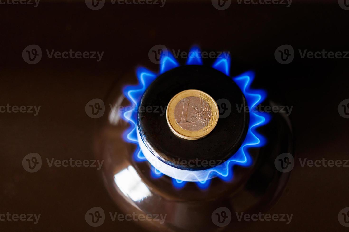Gasherdbrenner mit einer aufgelegten Ein-Euro-Münze, die Erdgas mit blauer Flamme verbrennt foto