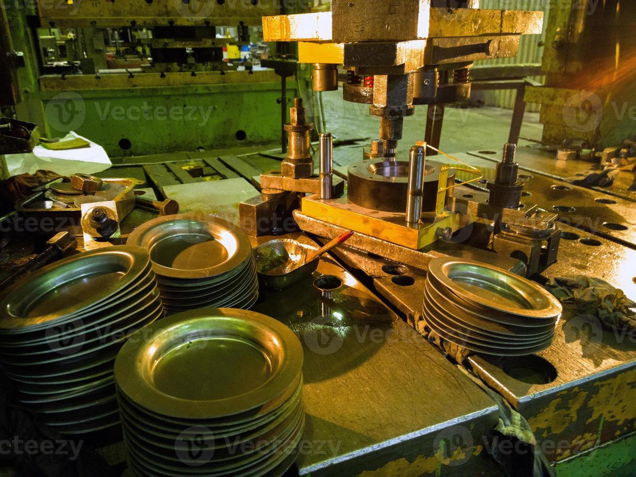Low-Tech-Stanzpresse zur Herstellung runder Aluminiumteile in dunkler Umgebung foto