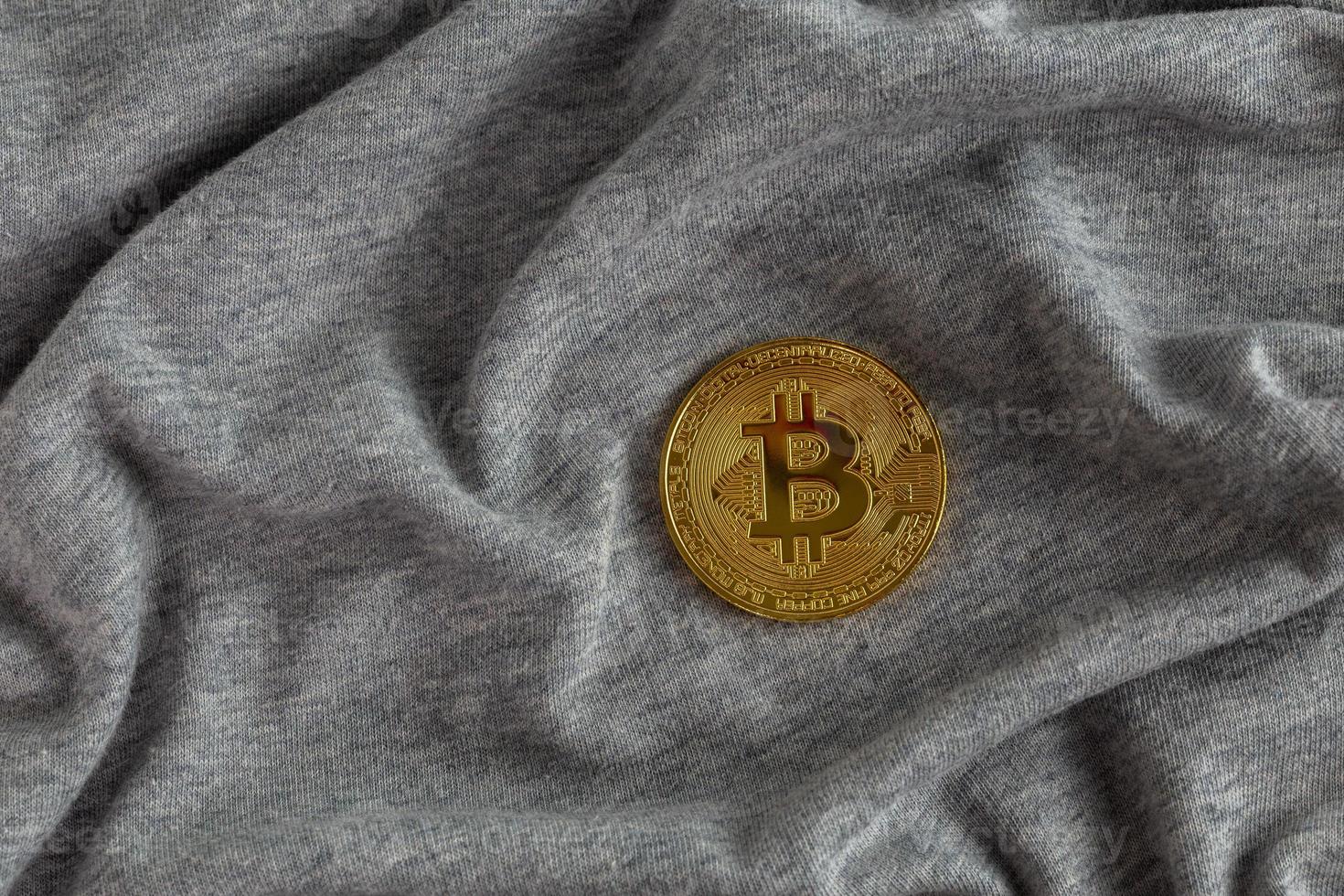 goldener bitcoin-shiner auf grauem, zerknittertem baumwolltuch foto