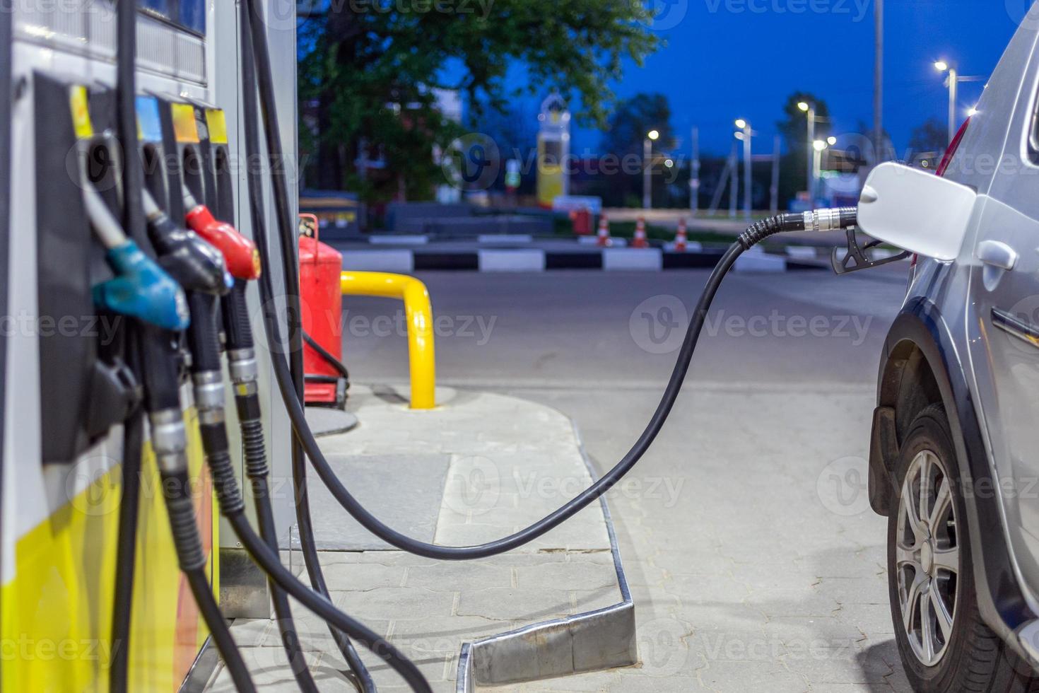 silbermetallic Autobetankung an Sommernacht Tankstelle - Nahaufnahme mit selektivem Fokus und verschwommenem Hintergrund foto