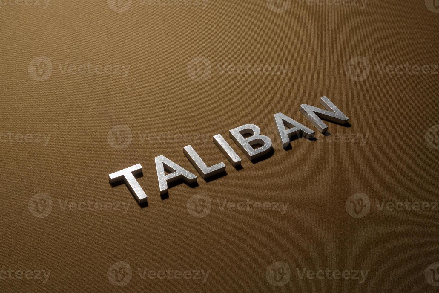 das wort taliban mit silbernen metallbuchstaben auf grobem khakifarbenem canvas-stoff foto