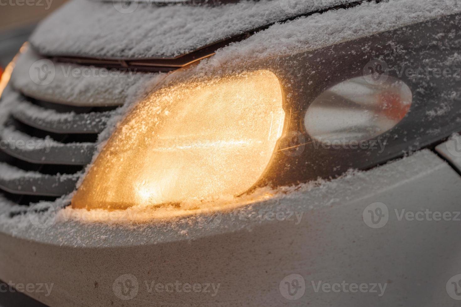 schneebedeckter Scheinwerfer eines weißen oder silbernen Zivilautos foto