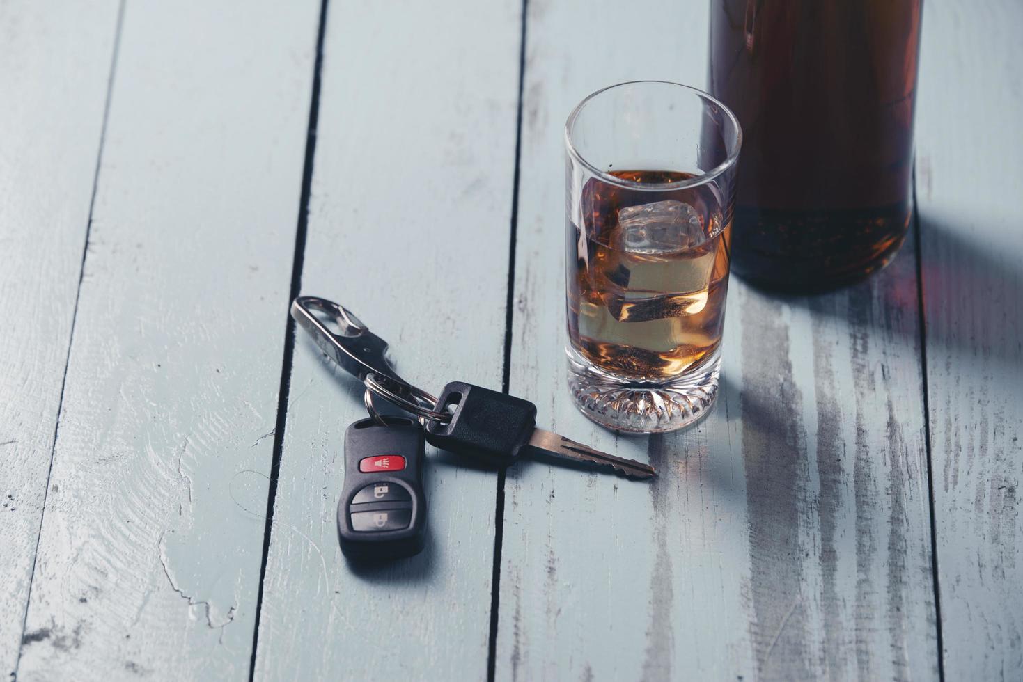 Glas, eine Flasche Alkohol und ein Autoschlüssel foto