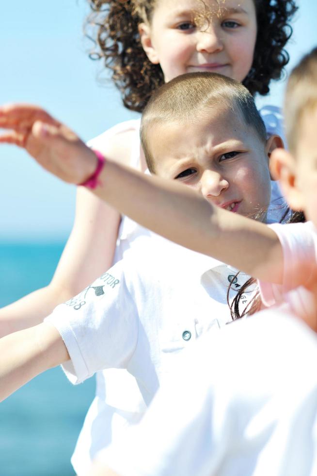 glückliche Kindergruppe, die am Strand spielt foto