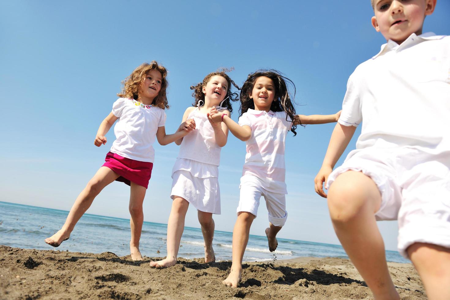 glückliche Kindergruppe, die am Strand spielt foto