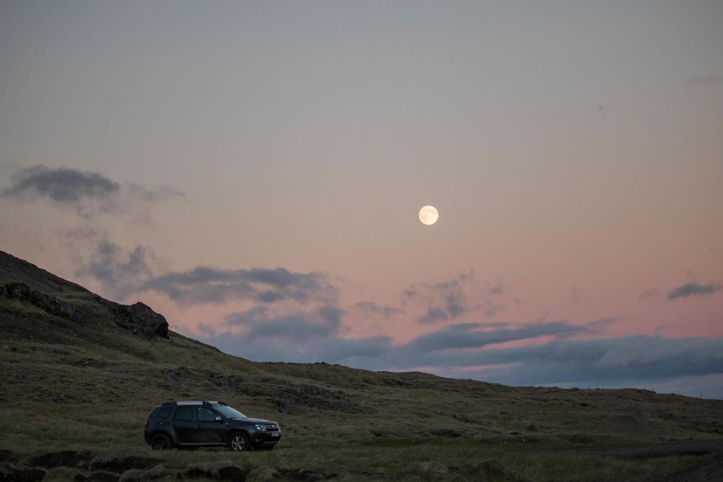 Auto auf Grasfeld bei Sonnenuntergang geparkt foto