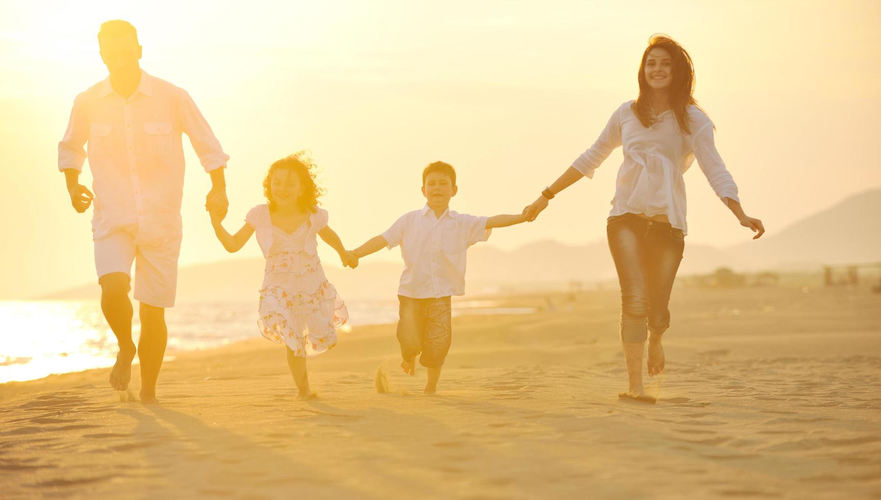 glückliche junge familie hat spaß am strand bei sonnenuntergang foto