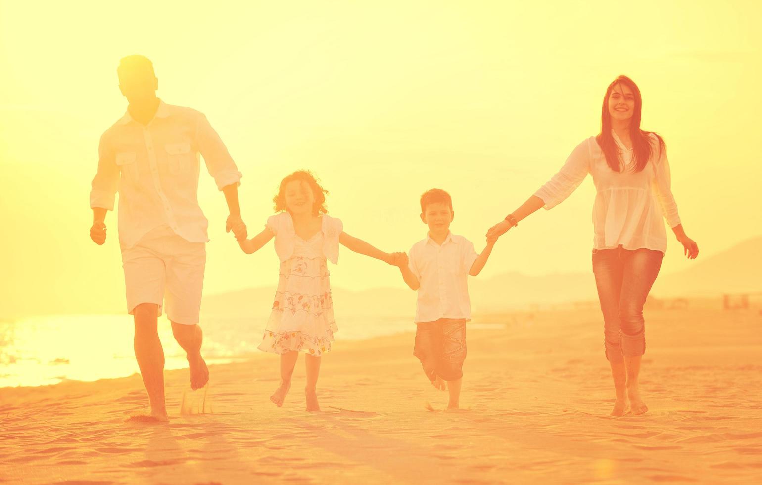 glückliche junge familie hat spaß am strand bei sonnenuntergang foto