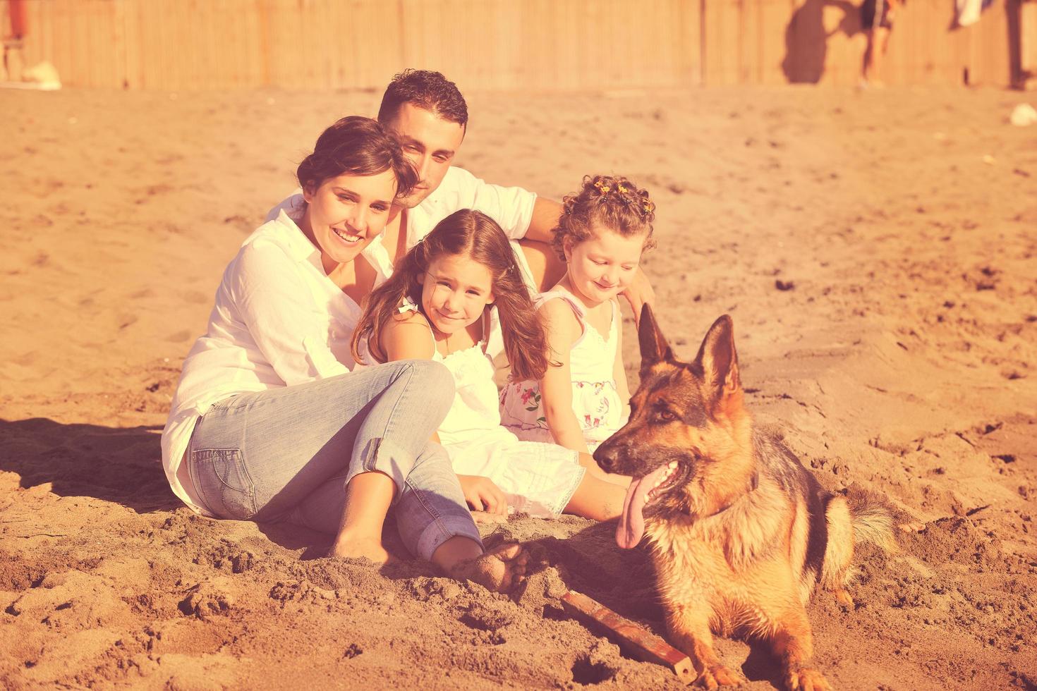 glückliche familie, die mit hund am strand spielt foto