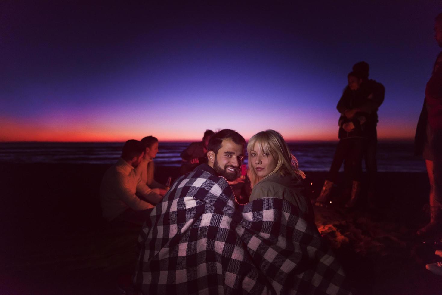 Paar genießt mit Freunden den Sonnenuntergang am Strand foto