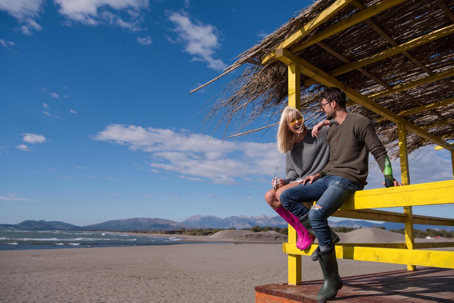 junges Paar trinkt gemeinsam Bier am Strand foto