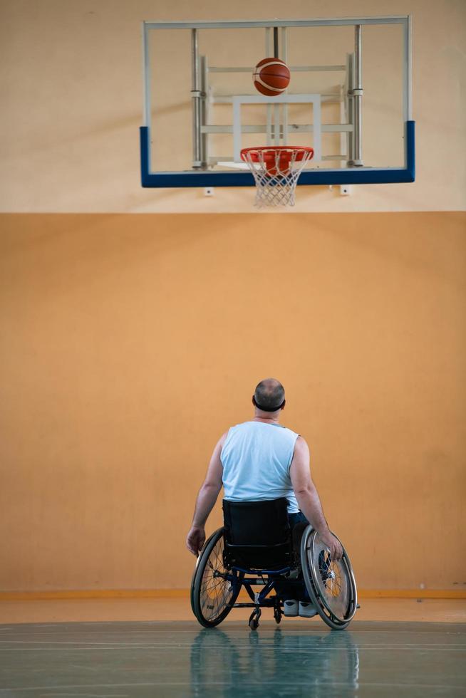 ein kriegsbeschädigter im rollstuhl trainiert mit einem ball in einem basketballverein beim training mit professionellen sportgeräten für behinderte. das Konzept des Sports für Menschen mit Behinderungen foto