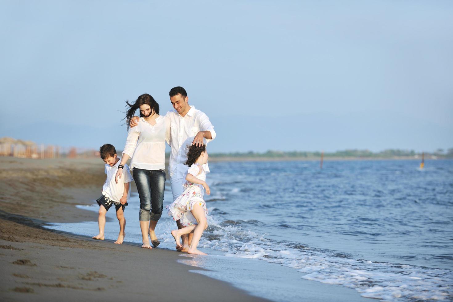 glückliche junge familie hat spaß am strand bei sonnenuntergang foto