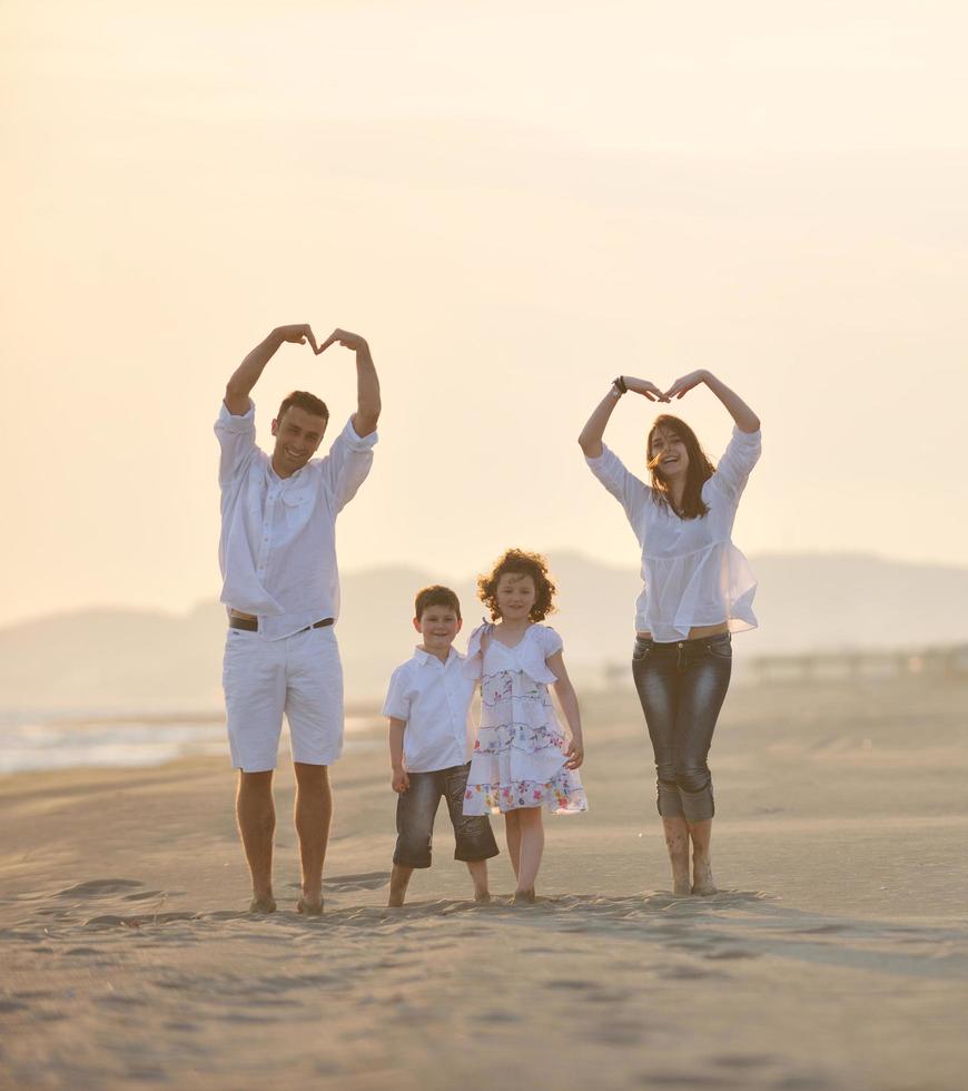 glückliche junge familie hat spaß am strand bei sonnenuntergang foto