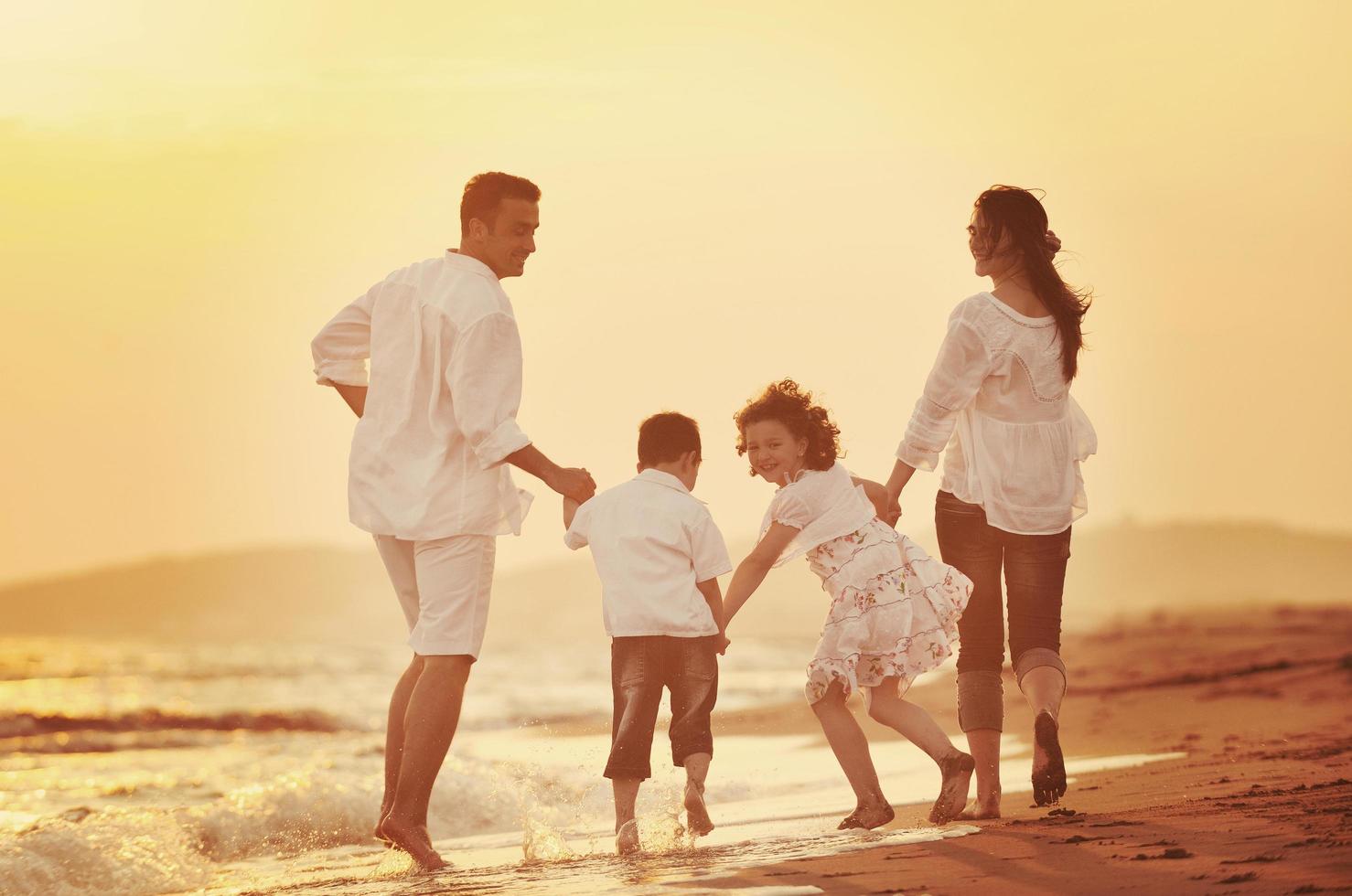 glückliche junge familie hat spaß am strand bei sonnenuntergang foto