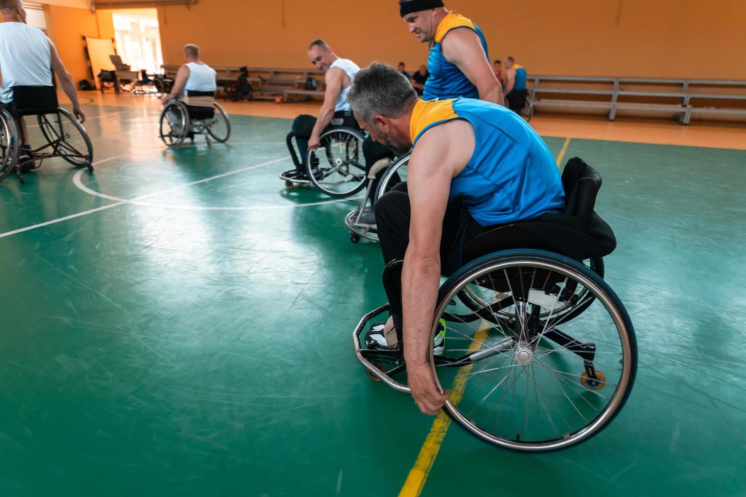 Behinderte Kriegsveteranen gemischte Rassen- und Alters-Basketballteams in Rollstühlen, die ein Trainingsspiel in einer Sporthalle spielen. Rehabilitations- und Inklusionskonzept für behinderte Menschen foto