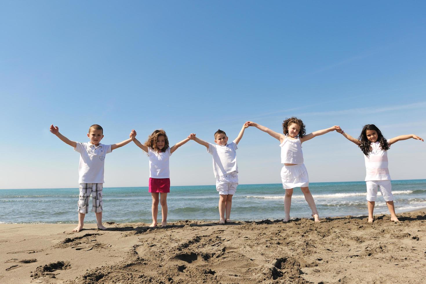 glückliche Kindergruppe, die am Strand spielt foto