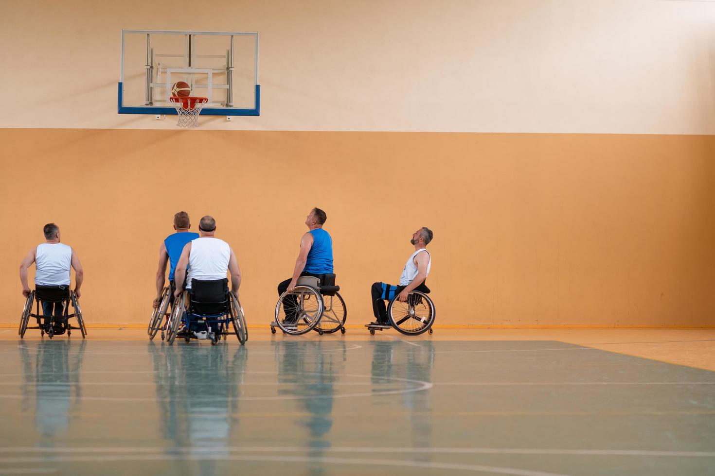 Behinderte Kriegsveteranen gemischte Rassen gegen Basketballmannschaften in Rollstühlen, die in Aktion fotografiert wurden, während sie ein wichtiges Spiel in einer modernen Halle spielten. foto